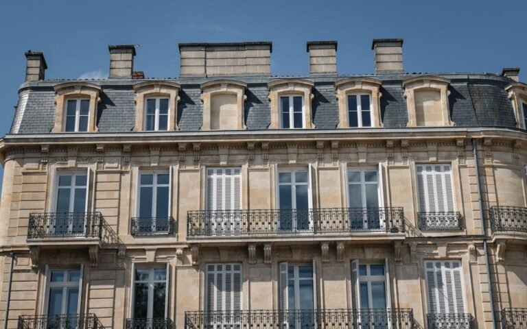 Façade en pierre d’un immeuble ancien avec balcons en fer forgé